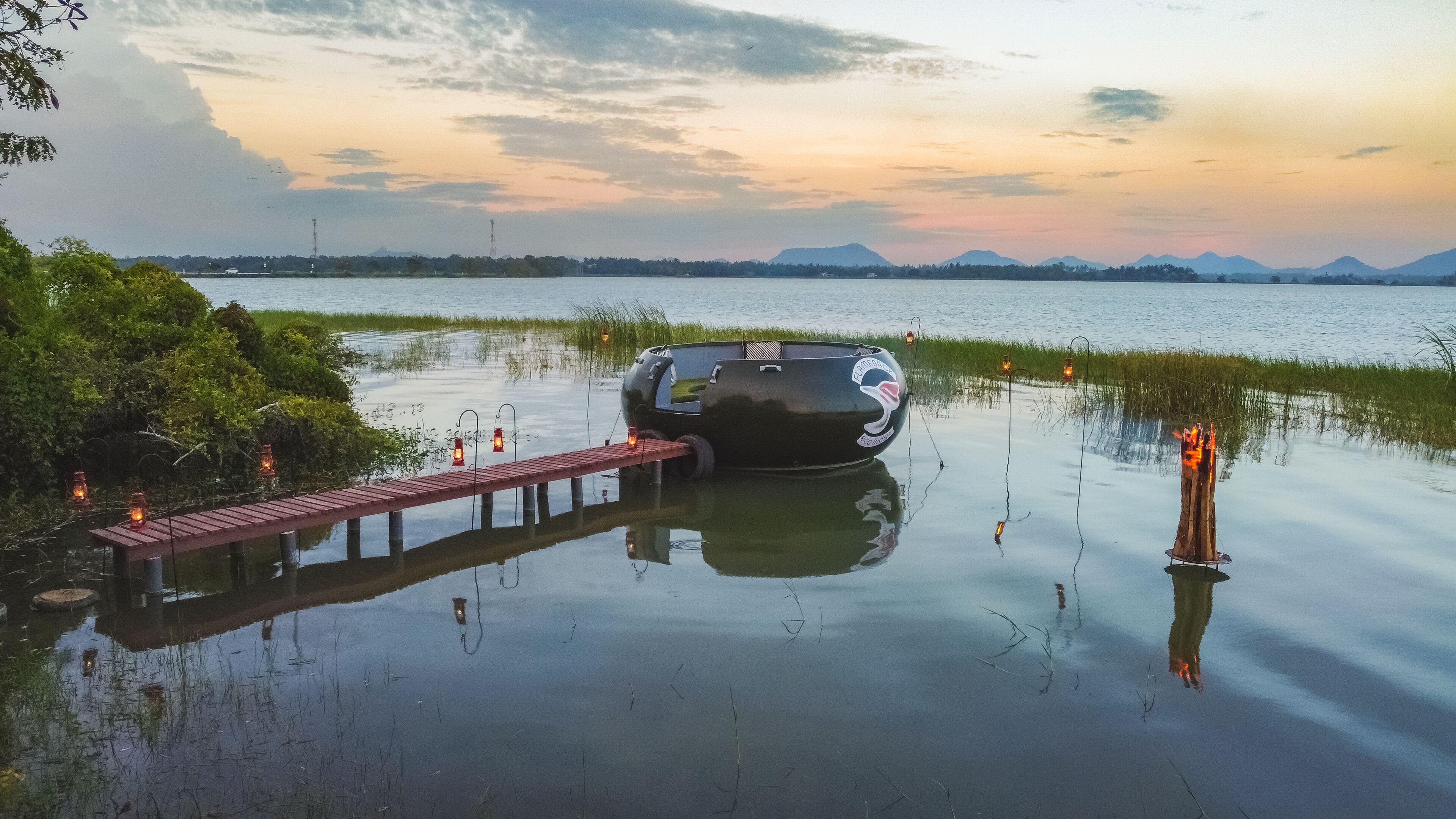 A boat docked at a pier with a view of a calm lake and distant mountains.