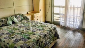 Une chambre à coucher avec un lit, une table de chevet, une armoire et une fenêtre avec des rideaux.