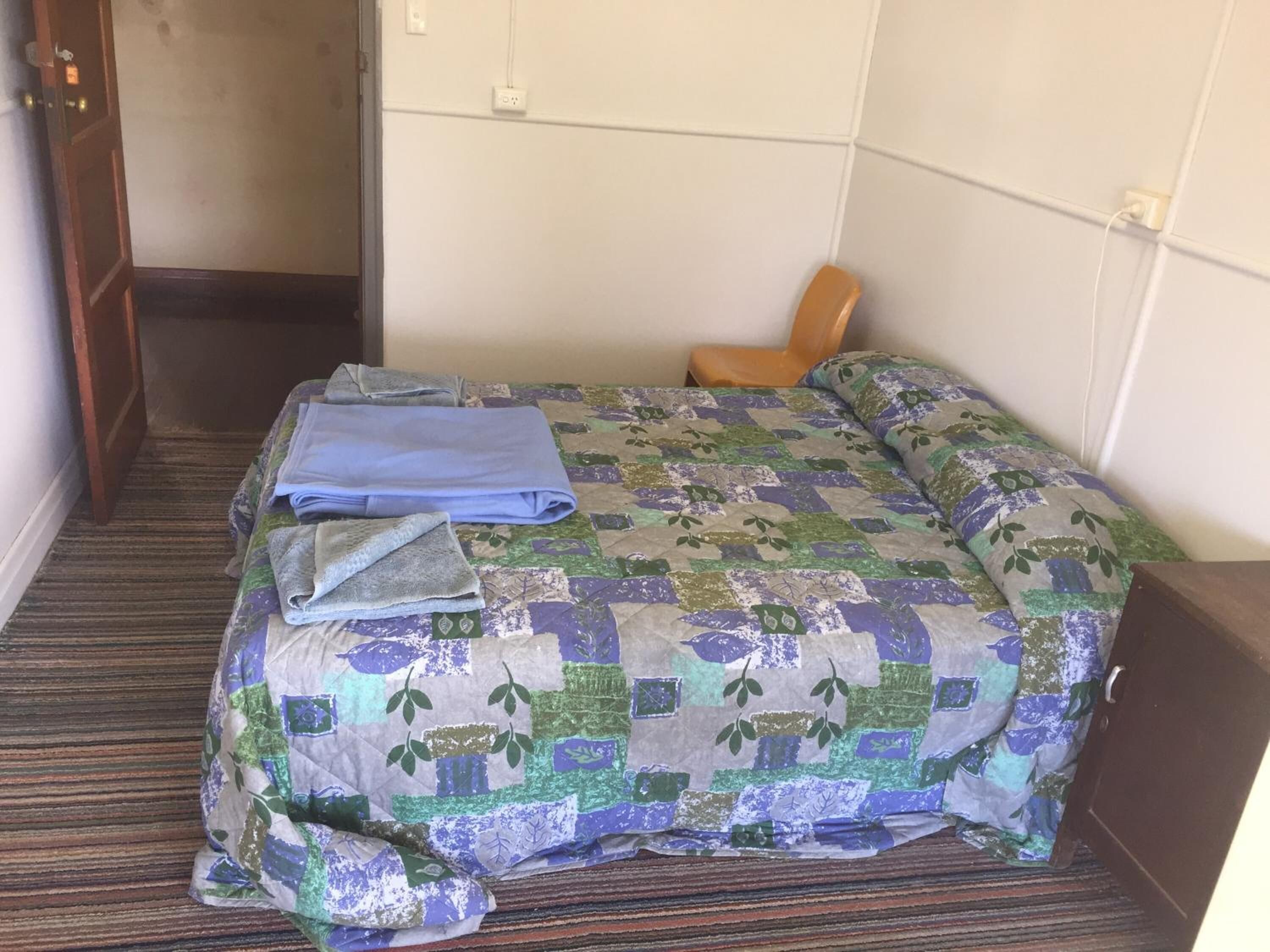 Una habitación de hotel con una cama, una silla y una puerta.