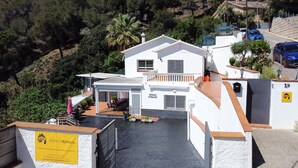 A two-story building with a balcony, a covered outdoor seating area, and a sign indicating it is a vacation rental.