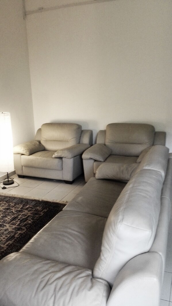 A living room with a sofa and two armchairs. - Homely Ground Apartment (Bandar Seri Begawan)