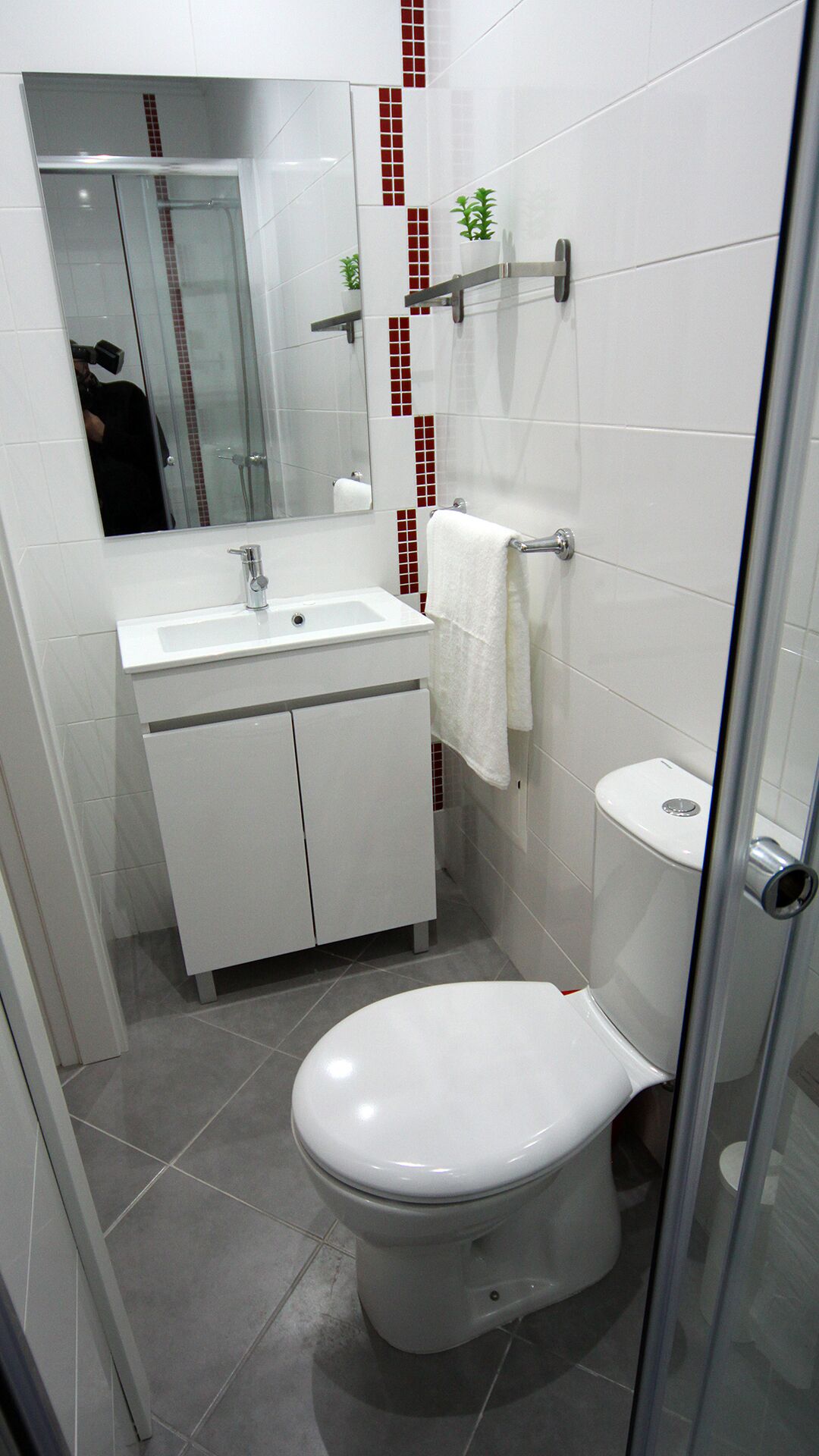 Ein kleines Badezimmer mit Toilette, Waschbecken und Spiegel.