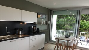 A modern kitchen with white cabinets, a black countertop, and a dining area with a table and chairs. - Nice sea view, south facing, Wifi, Parking, 50 m from beach & Thalasso (Quiberon)