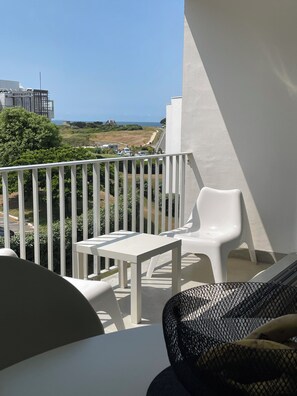 A balcony with a white table and chairs, overlooking a coastal landscape with buildings and a clear sky. - Nice sea view, south facing, Wifi, Parking, 50 m from beach & Thalasso (Quiberon)