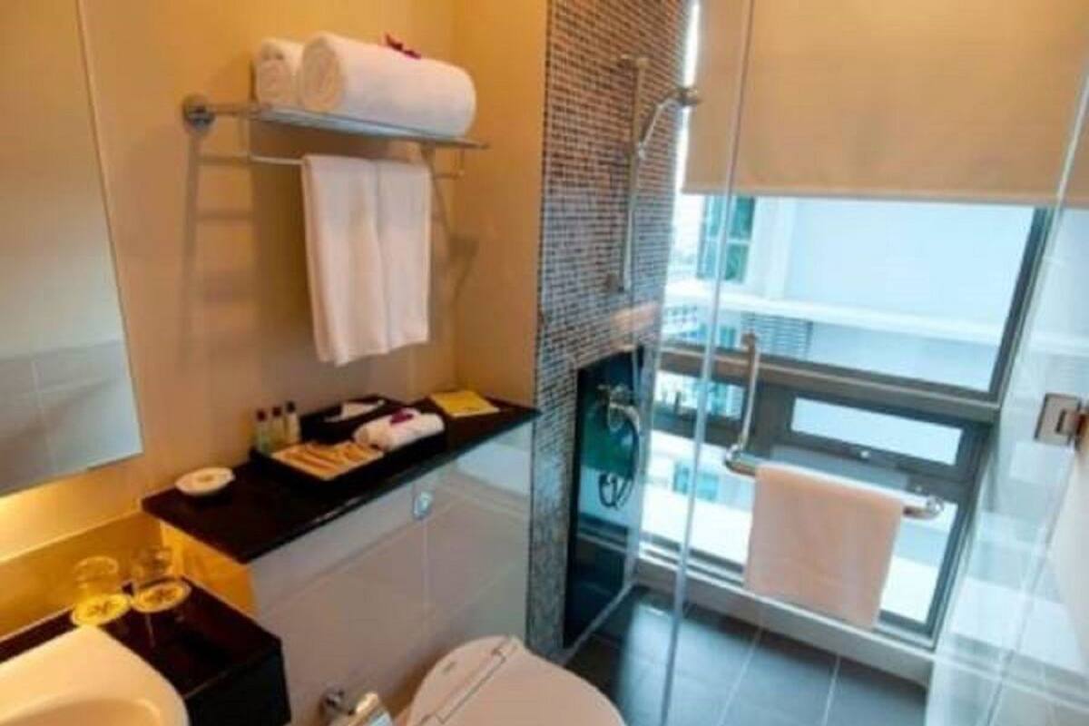 Un baño moderno con cabina de ducha de vidrio, inodoro, lavamanos y un perchero para toallas.