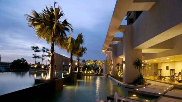 A modern hotel pool area with palm trees and a well-lit walkway. - Vinos Asia at Swiss Garden (Kuala Lumpur)