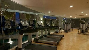 A gym with treadmills lined up against a glass wall, a wooden floor, and exercise equipment in the background. - Vinos Asia at Swiss Garden (Kuala Lumpur)