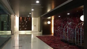 A modern hotel lobby with a polished floor, a red patterned carpet, and a metal railing along the wall. - Vinos Asia at Swiss Garden (Kuala Lumpur)