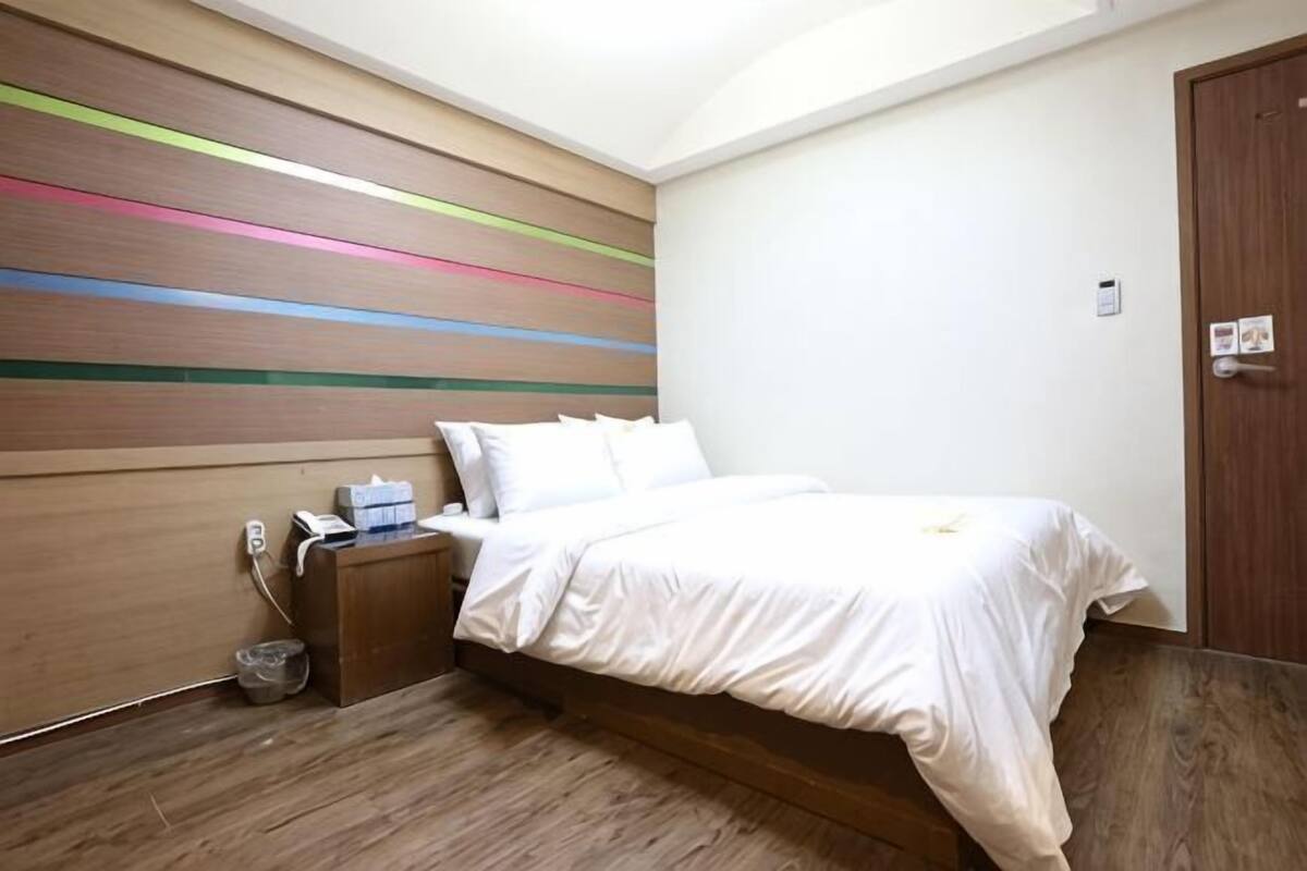 Une chambre à coucher avec un lit, une table de chevet et un mur orné de rayures horizontales.