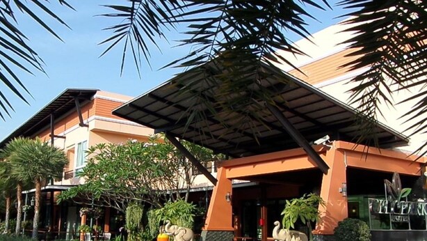 A hotel entrance with a covered walkway, palm trees, and two elephant statues.