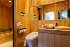 A wooden bathroom with a toilet, sink, and a mirror.