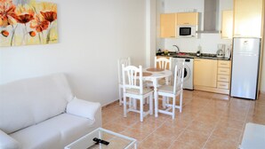 A compact living space with a sofa, dining table, chairs, a washing machine, a microwave, and a refrigerator. - Apartamento Sarah 2A, 2min to the beach and promenade, central and quiet. Free WIFI (Morro Jable)