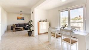 A modern living room with a sofa, coffee table, and a dining area with a table and chairs. - 1 bedroom cozy apartment in Medulin (Medulin)