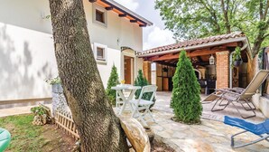 A patio area with a table and chairs, a small Christmas tree, and a covered seating area with a grill. - 1 bedroom cozy apartment in Medulin (Medulin)
