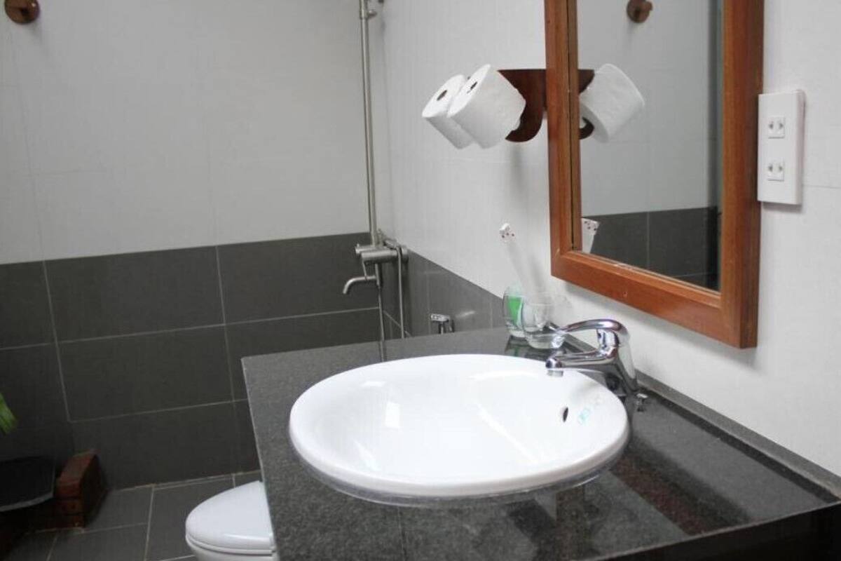 A bathroom with a white sink, a mirror, and two rolls of toilet paper on the wall.