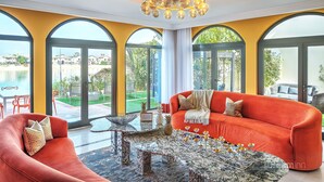 A modern living room with a red sofa, a marble coffee table, and large arched windows offering a view of the outdoors. - Dream Inn Dubai-Palm Island Retreat Villa (Dubai)