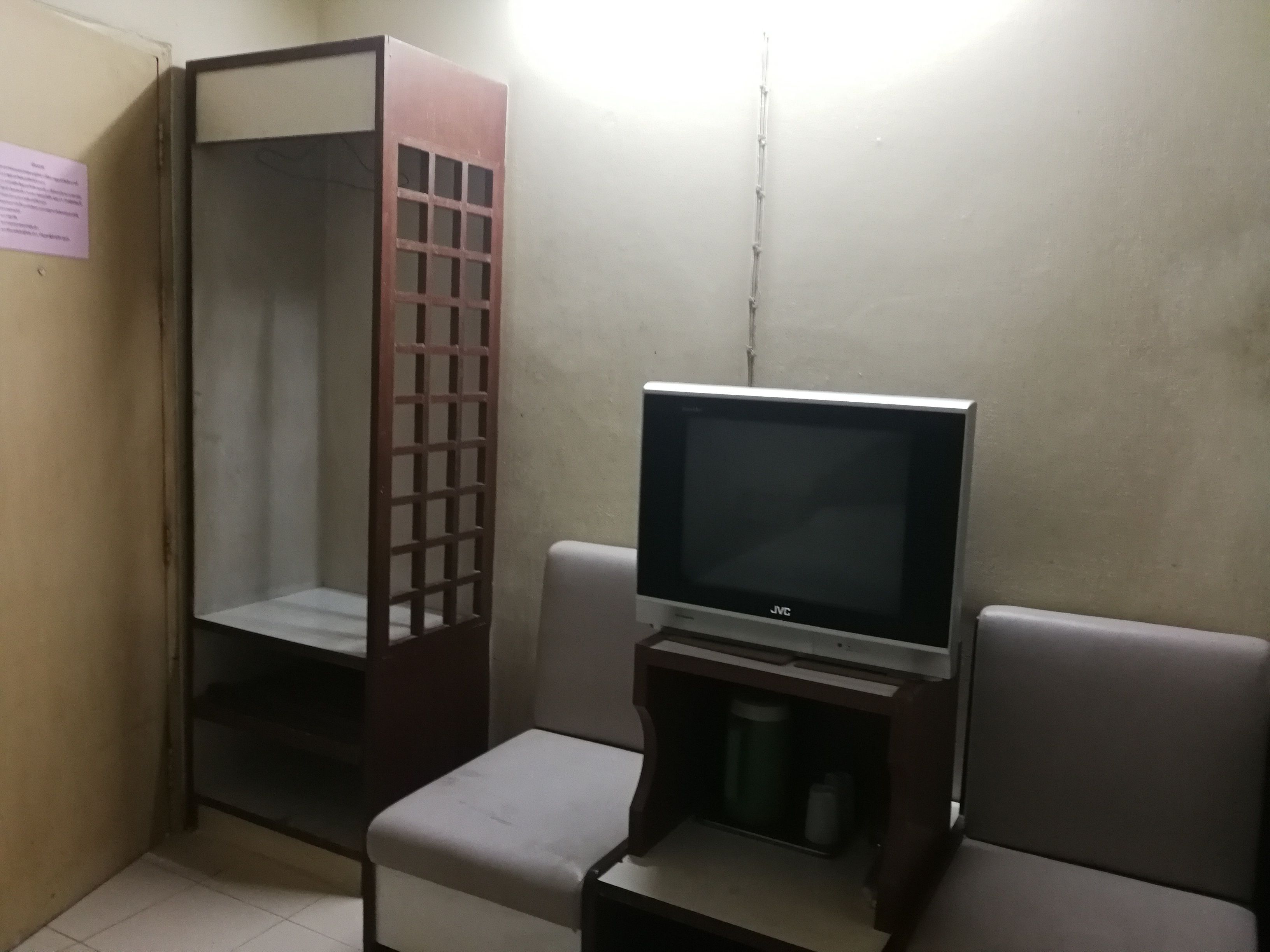 A small room with a television on a stand, a wooden cabinet, and a bench.