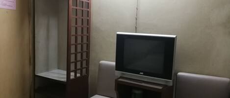 A small room with a television on a stand, a wooden cabinet, and a bench.