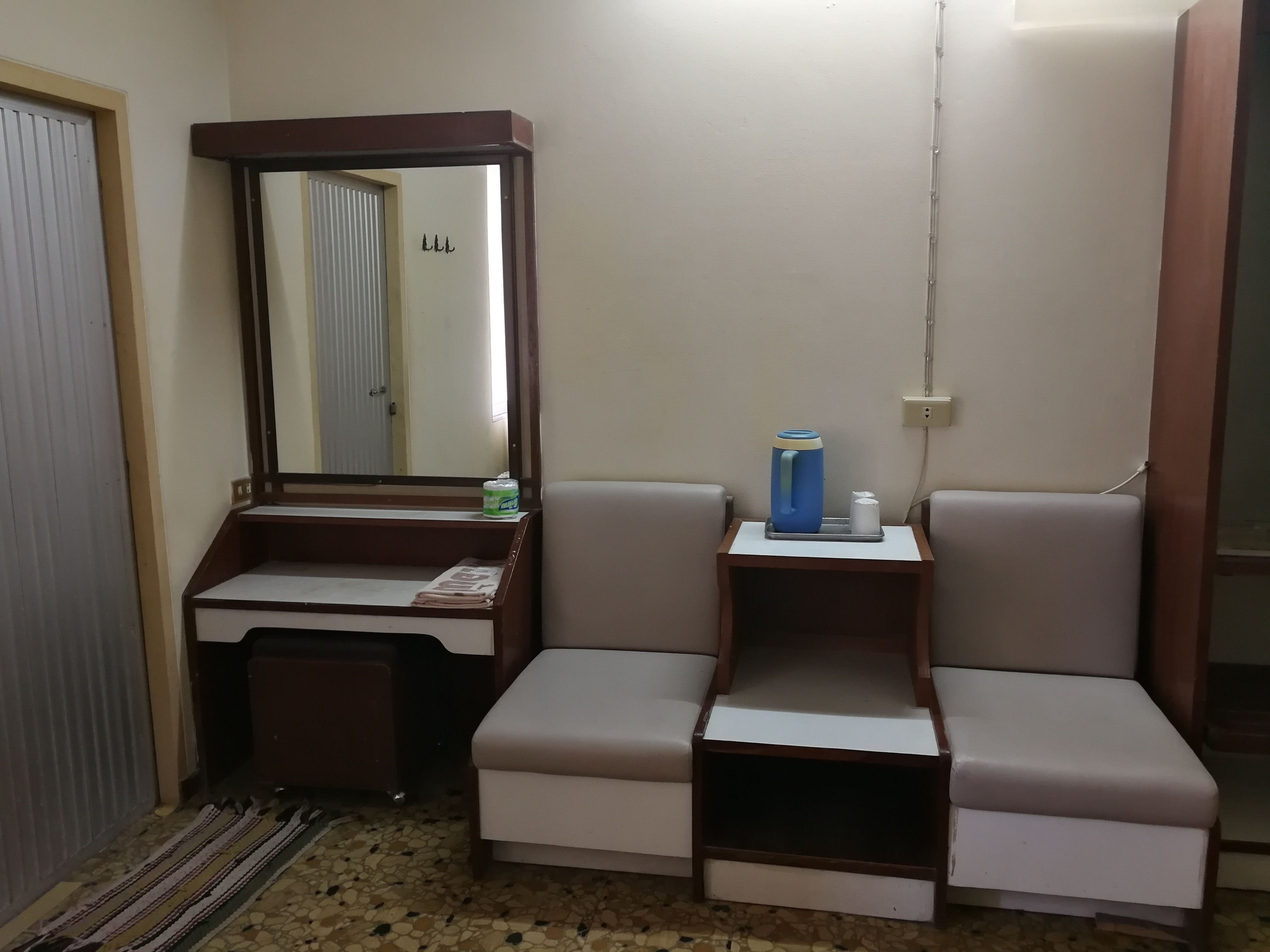 A compact bathroom with a vanity, mirror, and a small seating area.