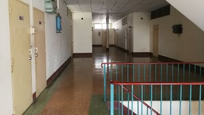 Ein langer, schmaler Flur mit Türen an einer Seite und einer Treppe an der anderen.