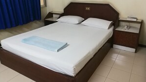 Ein ordentlich bezogenes Bett mit weißen Leinen und einem blauen Handtuch, ein Holz-Kopfteil, zwei Nachttische mit Lampen und ein Telefon.