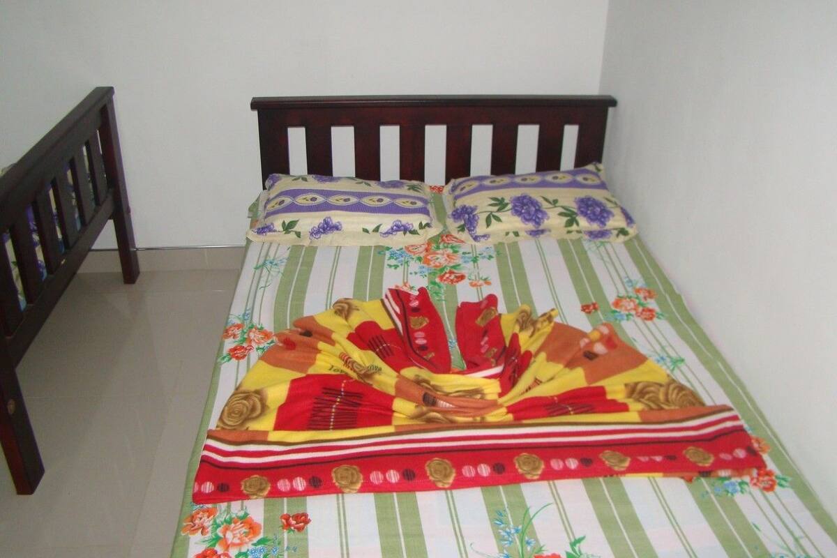 A bed with a striped bedspread and floral pillows.