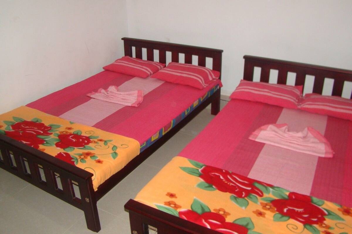 Two single beds with wooden frames and colorful floral bedspreads.