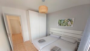 Ein Schlafzimmer mit einem Bett, einem Nachttisch, einer Hängelampe und einer Tür zu einem anderen Raum.