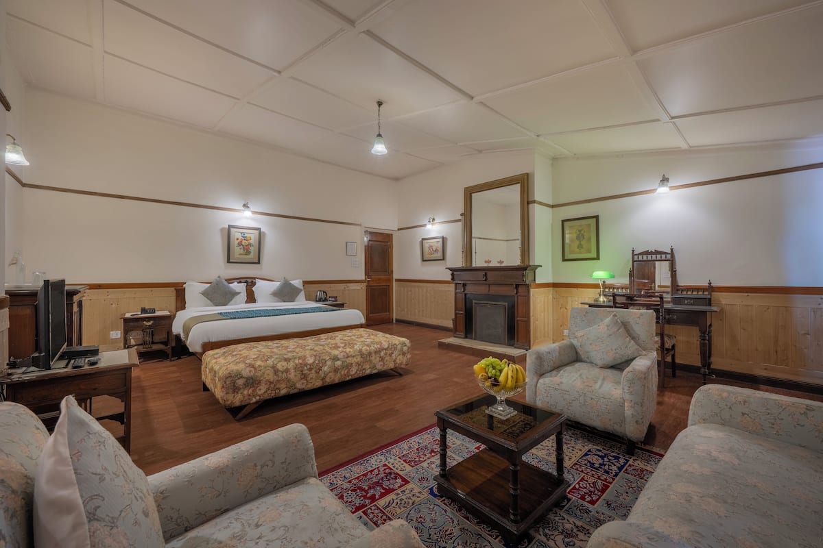 Una habitación amplia con una cama grande, chimenea, televisor y comedor.