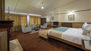 A hotel room with a large bed, two armchairs, a sofa, a television, and a wooden cabinet. - Springfields by Eastlynn Collections - A Heritage Palace Since 1902 (Shimla)