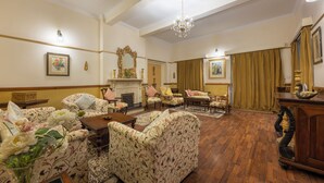 A spacious living room with floral-patterned sofas, a wooden coffee table, and a chandelier. - Springfields by Eastlynn Collections - A Heritage Palace Since 1902 (Shimla)