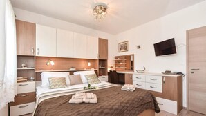 A bedroom with a bed, bedside tables, a desk, a chair, a TV, and a wardrobe. - Cozy home in Split with private swimming pool, can be inside or outside (Split)