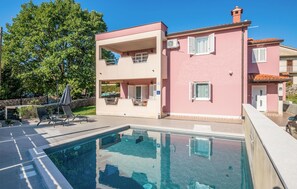 Un bâtiment à deux étages doté d’une piscine, d’un espace extérieur aménagé et d’un mur en pierre.