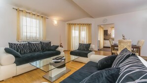 A living room with two sofas, a coffee table, and a dining area with a table and chairs. - Amazing home in Labin (Labin)