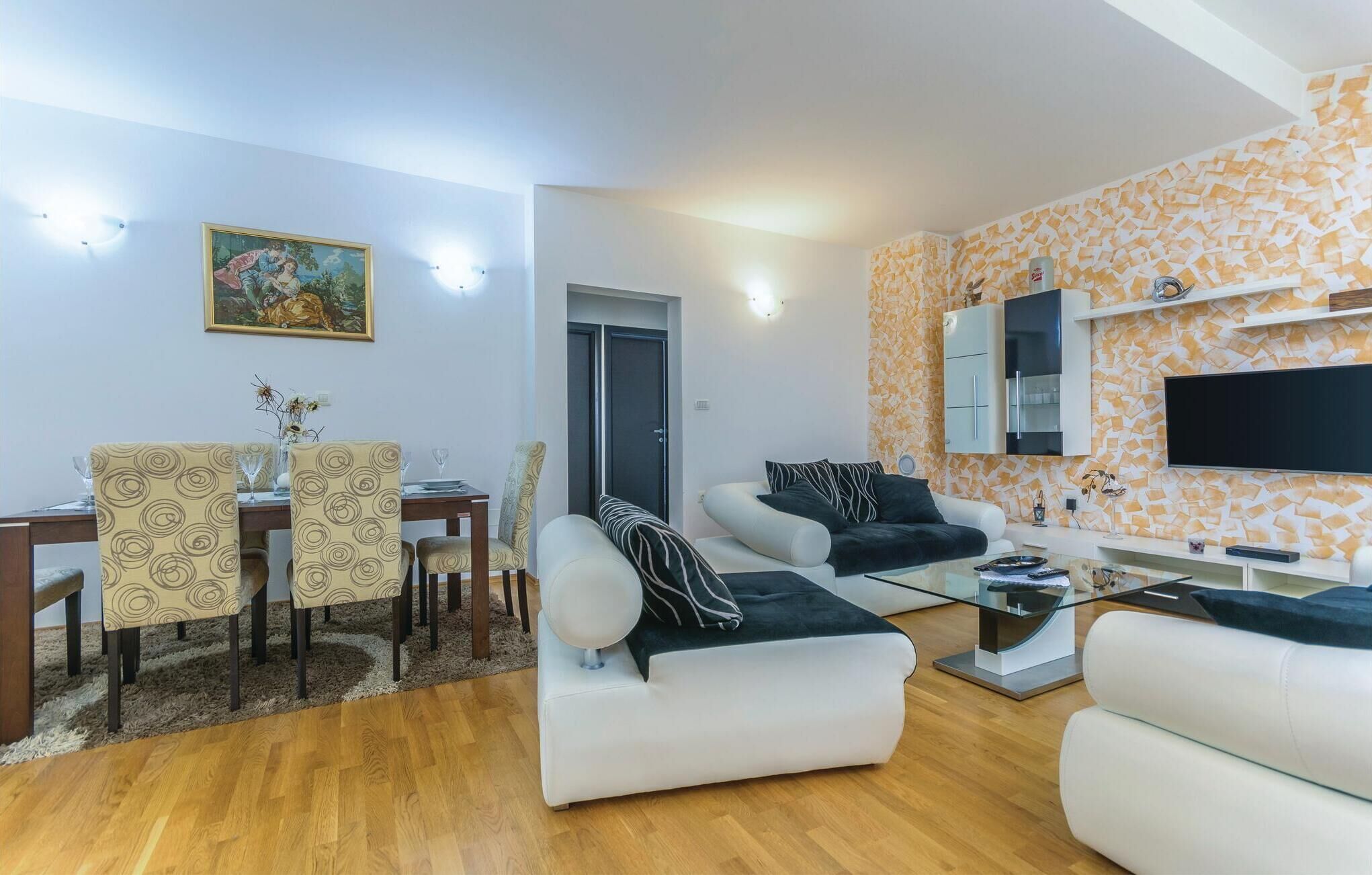 Ein modernes Wohnzimmer mit Essbereich, einer Sofagarnitur, einem Flachbildfernseher und einer Wand mit Muster.
