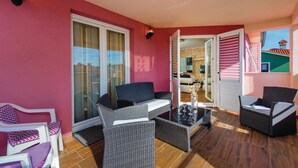 A balcony with wicker furniture, a glass door leading to a room, and a view of a building. - Amazing home in Labin (Labin)