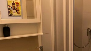 A bathroom with a white sink, a mirror, and a shower enclosure.