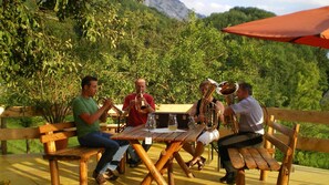 Un grup de persones assegudes a una taula de fusta a l'aire lliure, amb muntanyes al fons.