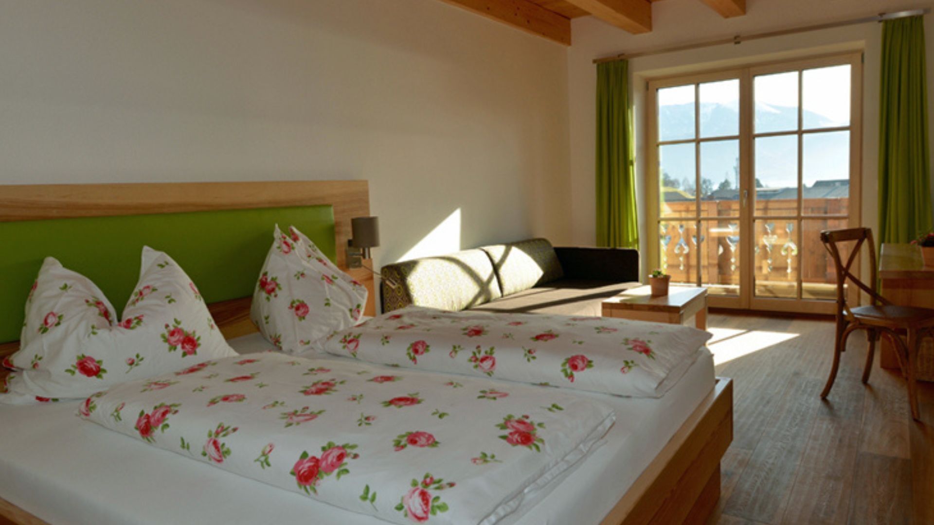 Ein Hotelzimmer mit zwei Betten, einem Schlafsofa, einem Tisch und Blick auf die Berge.