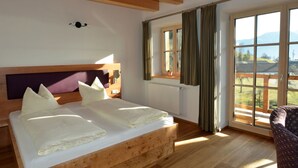 Una habitación con una cama de madera, una ventana con cortinas y vistas al exterior.