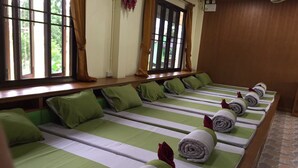 A row of single beds with green and white striped bedding, neatly made with rolled towels and pillows. - Sasi Resort (Song Phi Nong)