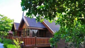 A traditional wooden house with a sloped roof and a balcony. - Sasi Resort (Song Phi Nong)