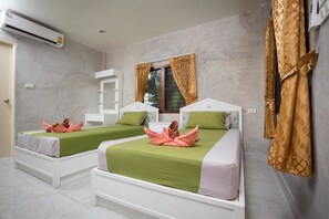 A hotel room with two beds, a window with curtains, an air conditioning unit, and a white wardrobe.