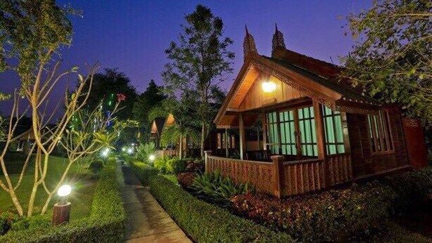 A traditional wooden house with a porch, surrounded by well-maintained hedges and trees. - Sasi Resort (Song Phi Nong)