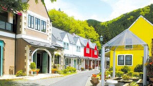 A street lined with colorful buildings, including a yellow house with a garden. - Hotel Euro City (Nikko)