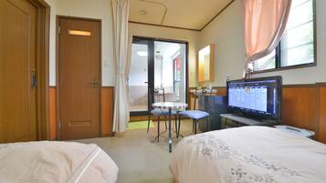 Ein Hotelzimmer mit zwei Betten, einem Fernseher, einem Schreibtisch und einem durchgegangenen Badezimmer.