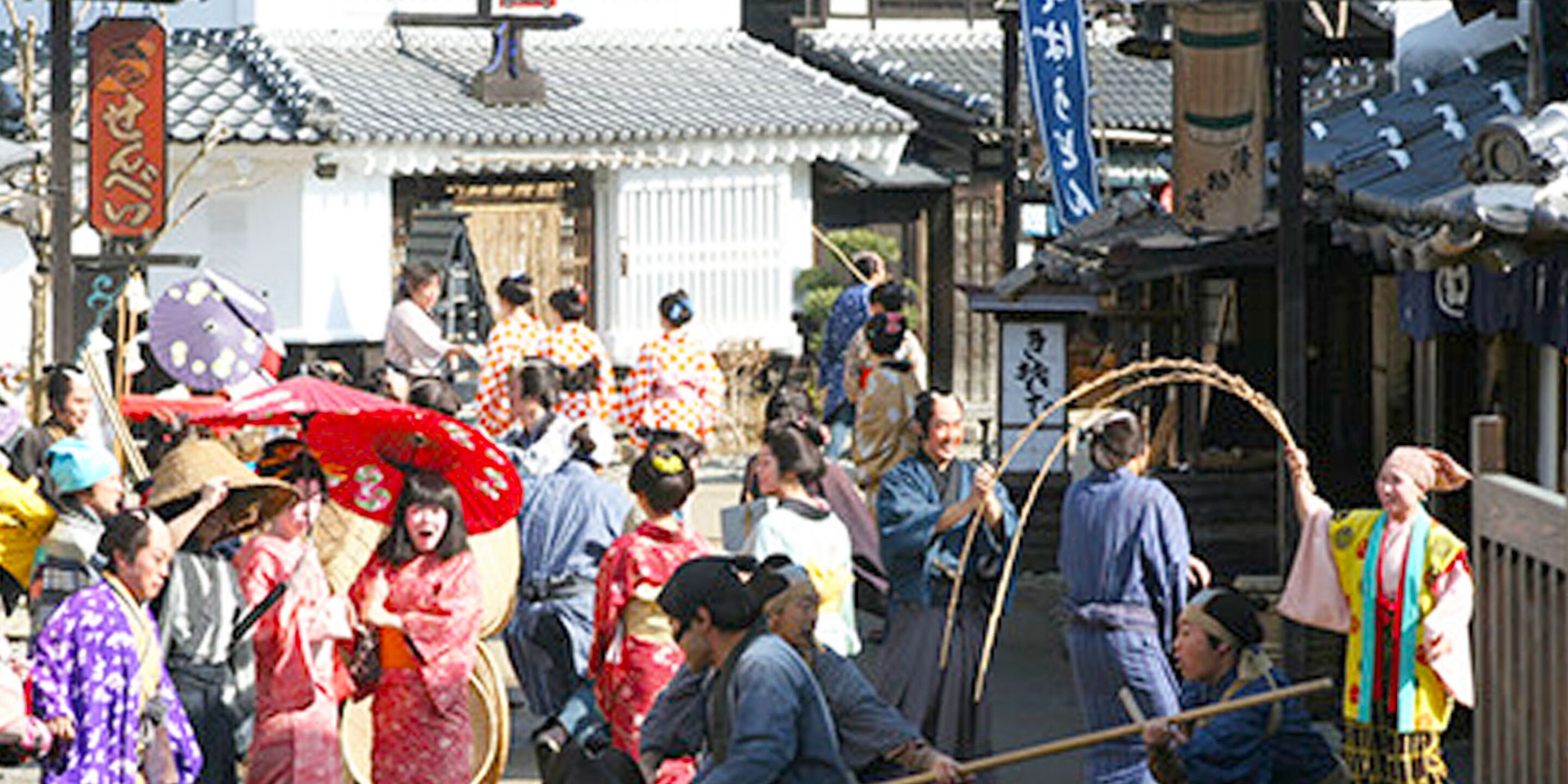 A traditional Japanese street scene with people in kimonos, a shrine, and traditional buildings.