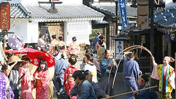 A traditional Japanese street scene with people in kimonos, a shrine, and traditional buildings.