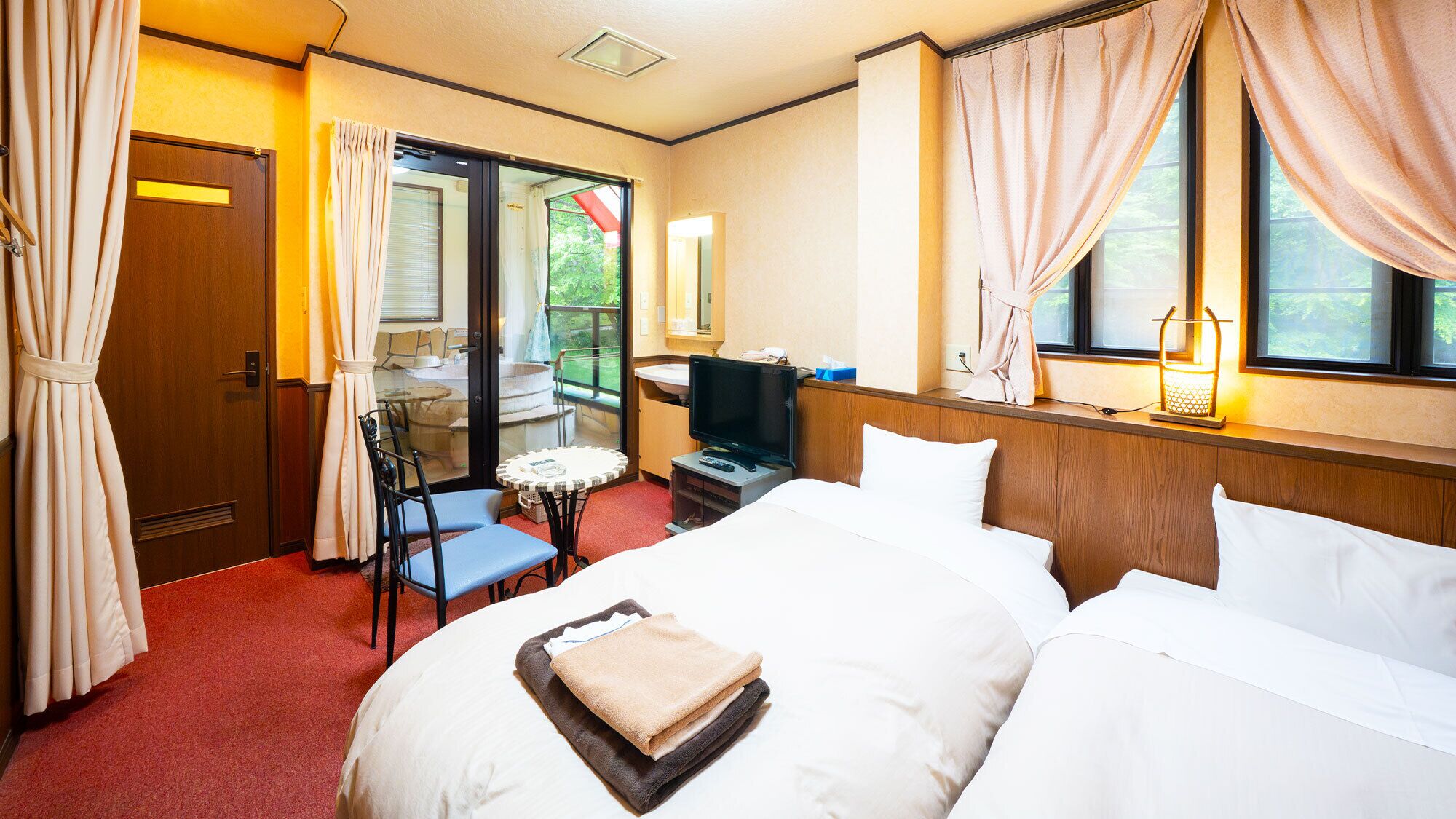 A hotel room with a bed, a television, a small table, and a chair.