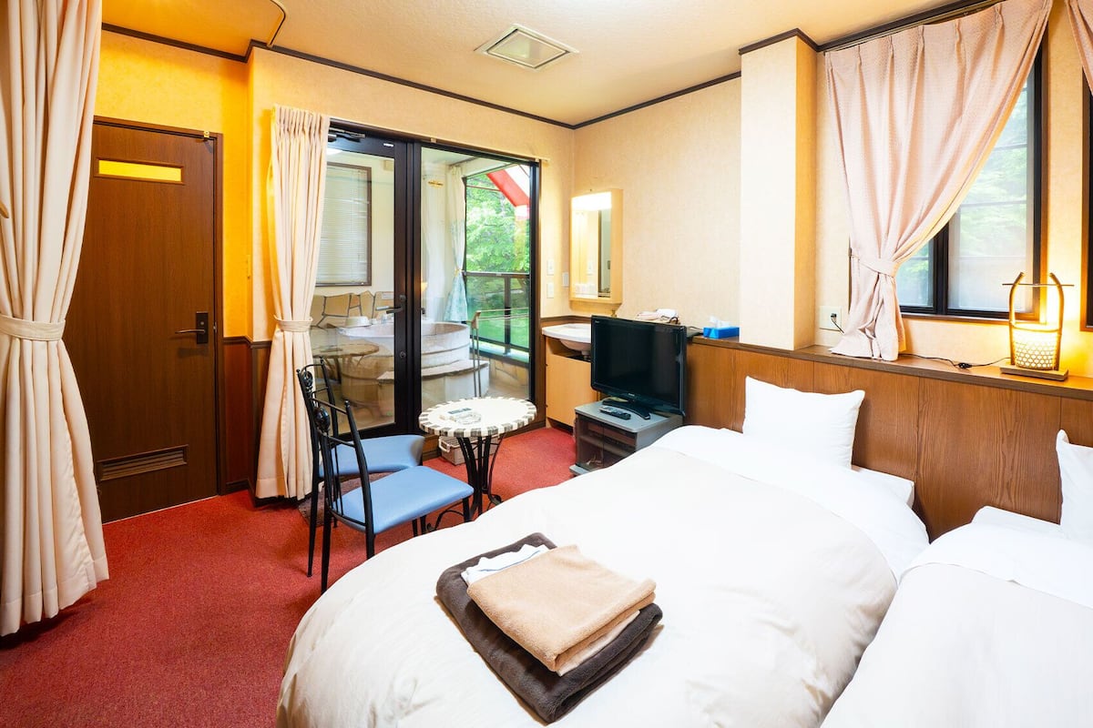 A hotel room with a bed, a television, a small table, and a chair.